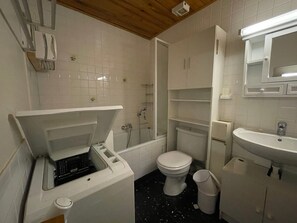 A compact bathroom with a toilet, sink, and shower.