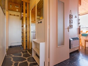 A narrow hallway with a stone-patterned floor, wooden cabinets, and a white radiator.