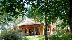 Eine Holzhütte mit Ziegeldach, umgeben von dichtem Grün und Bäumen.