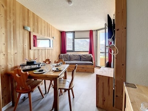 Ein Holzinnenraum mit einem Esstisch, Stühlen, einer Couch und einem Fernseher.