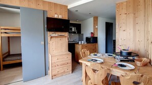 Une chambre compacte et moderne, dotée d’une kitchenette, d’un coin repas avec des meubles en bois et d’un lit superposé.