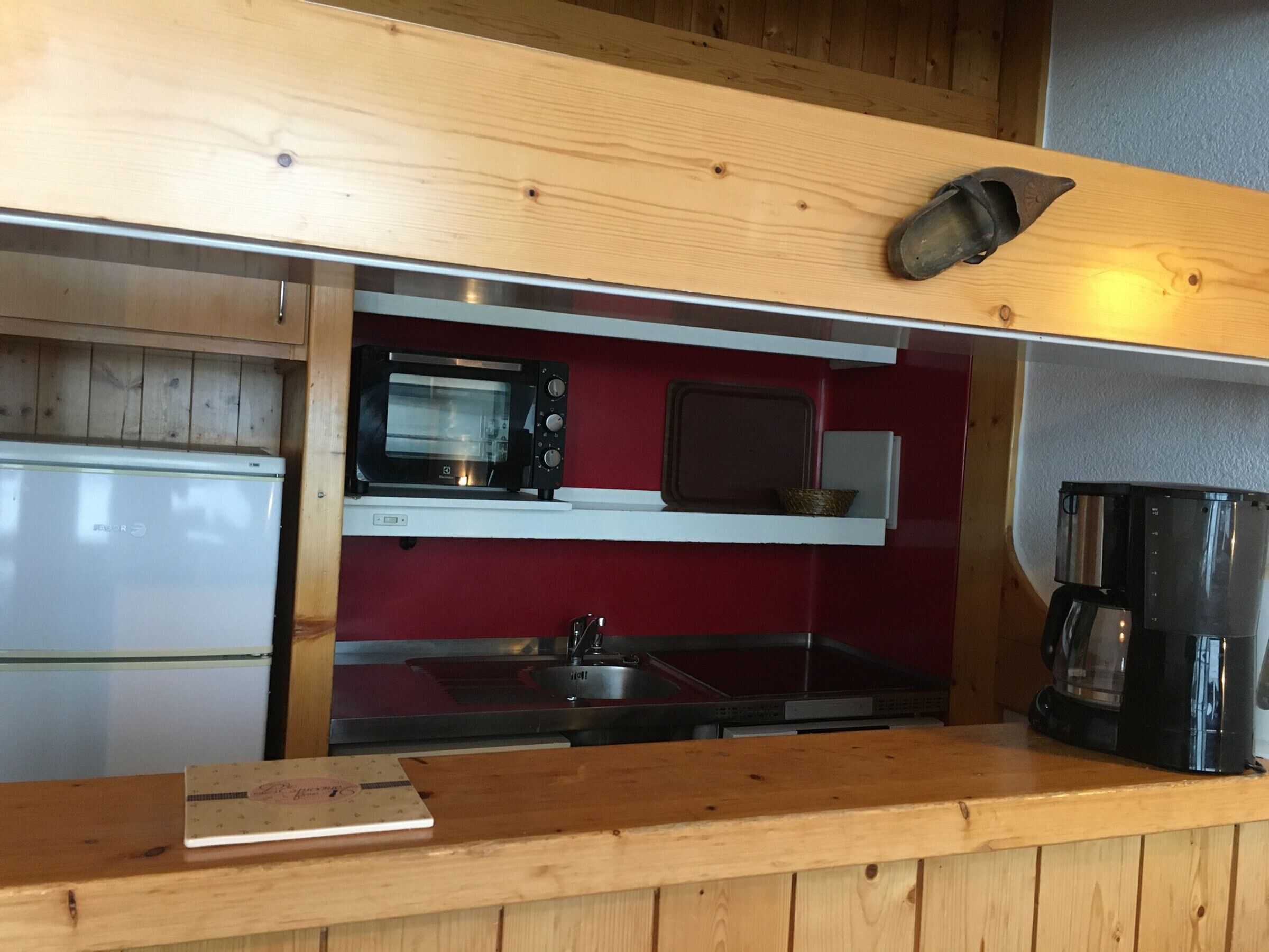 Een kleine keuken met een magnetron, koffiezetapparaat en een klein spoelbakje.