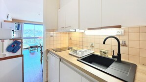 Eine moderne Küche mit weißen Schränken, einem schwarzen Spülbecken und Blick auf Berge durch das Fenster.
