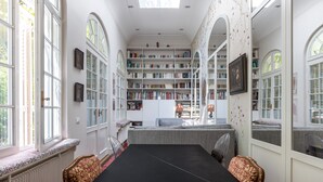 A spacious library with high ceilings, large windows, and a central black table. - The Arbour, by Veeve (Paris)