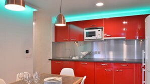 Una cocina moderna con armarios rojos, electrodomésticos de acero inoxidable e iluminación colgante.