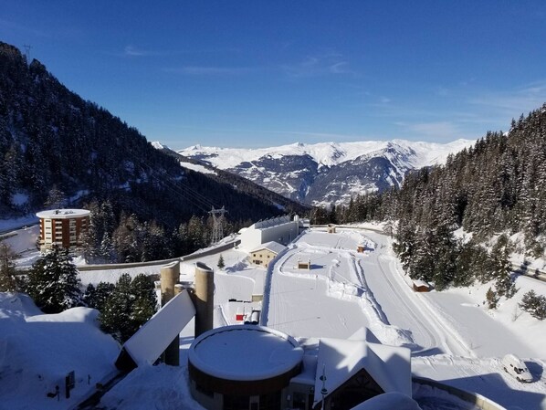 A snow-covered mountain town with buildings, a road, and a view of snow-capped mountains.