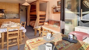 A cozy room with a bed, a dining table, and a kitchen area. - Bright studio in Les Menuires, ski-in/ski-out, balcony (Les Menuires)