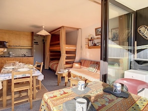 Une pièce confortable comprenant un lit, une table à manger et un coin cuisine.