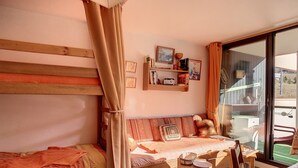 A cozy bedroom with a bed, a small table, and a window with curtains. - Bright studio in Les Menuires, ski-in/ski-out, balcony (Les Menuires)