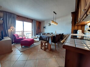 Eine moderne Küche mit Essbereich, einem roten Sessel und einem großen Fenster mit Vorhängen.
