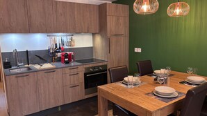 A modern kitchen with wooden cabinets, a stainless steel sink, and a dining area with a wooden table and chairs. - Les Gets: 2-bed apartment with terrace and WIFI, near center and slopes (Les Gets)