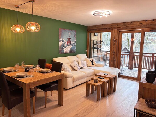 A cozy living room with a wooden dining table, a sofa, and a painting on the wall.