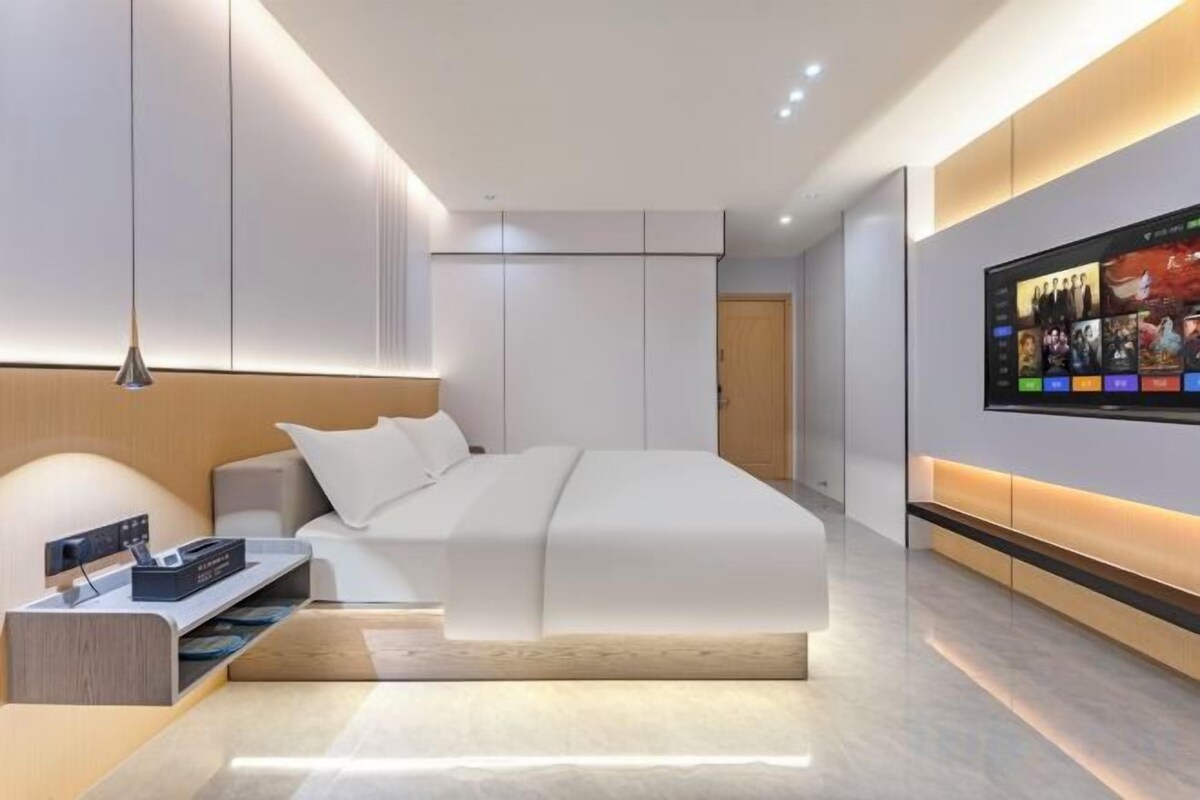 Une chambre moderne avec un grand lit, un téléviseur intégré et une table de chevet.