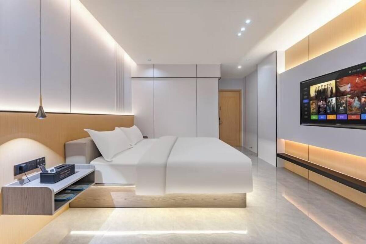 A modern bedroom with a bed, bedside table, TV, and built-in wardrobe.