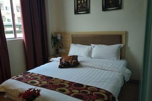 Une chambre d’hôtel avec un lit, une fenêtre avec des rideaux et deux tableaux accrochés au mur.