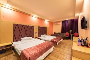 Une chambre d’hôtel avec deux lits, un bureau, une chaise, une télévision et une petite table avec une plante.