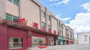 Un edificio con toldo rojo y señalización, con múltiples ventanas y cielo despejado.