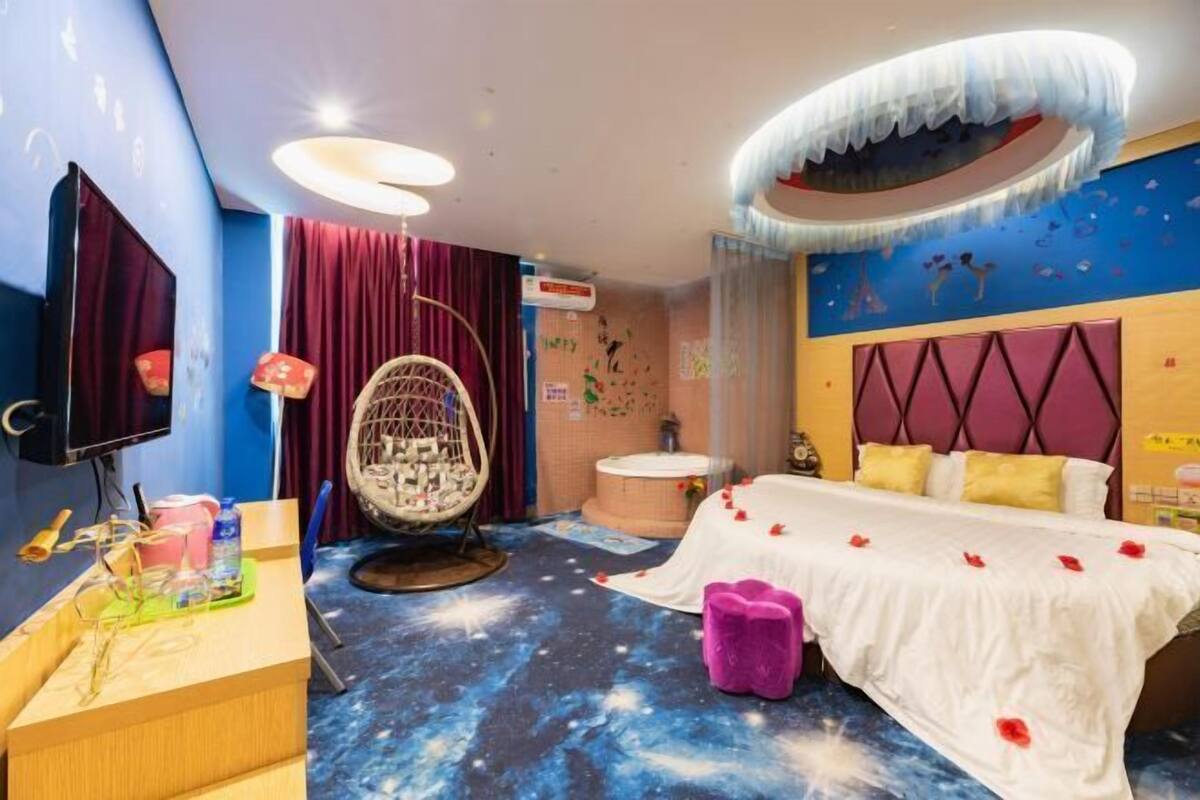 A room with a bed, a desk, a chair, and a ceiling light fixture.