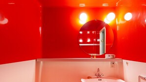 Een badkamer met een wit wastafel, een spiegel en rode wanden.