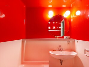 Een badkamer met een wit wastafel, een spiegel en rode wanden.