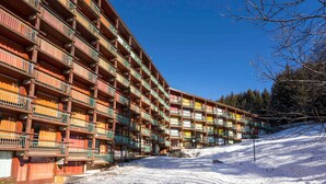 A multi-story hotel with balconies, set against a snowy landscape. - Renovated ski-in studio with balcony (Les Arcs 1800)