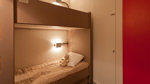 A bunk bed with a headboard, a bedside lamp, and a teddy bear on the lower bed. - Renovated ski-in studio with balcony (Les Arcs 1800)