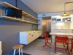 Een moderne keuken met witte kastjes, een ingebouwde magnetron en een flatscreen televisie bevestigd aan een houten plank.