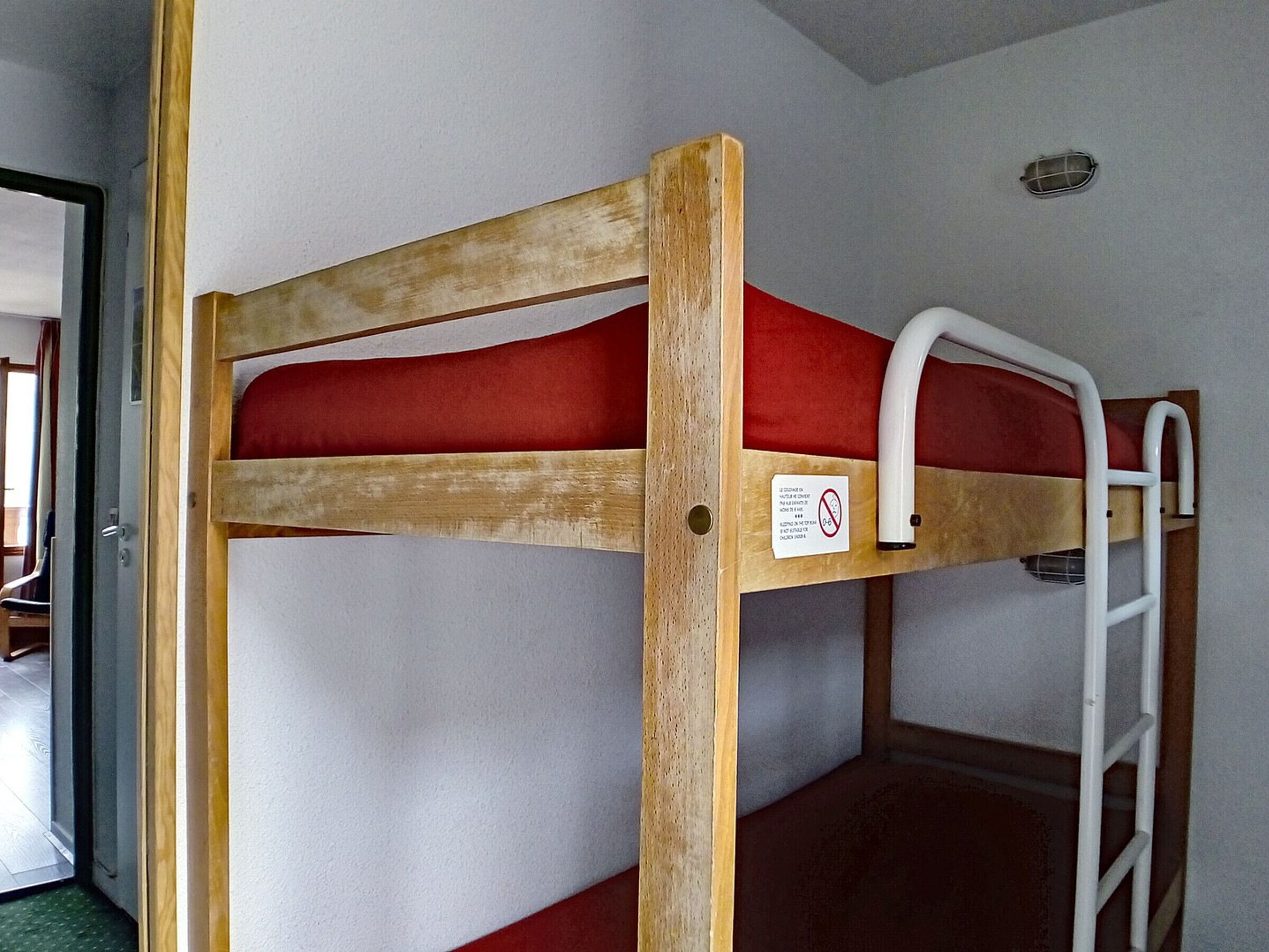 Letto a castello con materasso rosso e scaletta bianca.