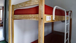 A bunk bed with a red mattress and a white ladder.