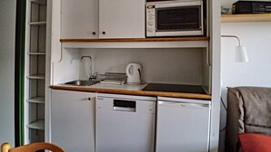 A compact kitchenette with a microwave, a kettle, and a dishwasher.
