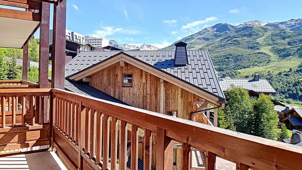 A wooden cabin with a balcony overlooking a mountainous landscape.