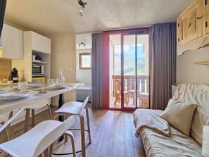 Ein kompakter Wohnraum mit Essbereich, Küchenzeile und einem Balkon mit Blick.