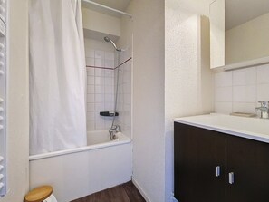 Ein Badezimmer mit einer Badewanne, einer Dusche, einem Waschbecken und einem Spiegel.