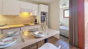 Et moderne køkken med hvide skabe, en træbordplade og et spiseområde med et bord dækket til to.