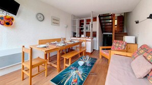 Un espacio habitable compacto con comedor, kitchenette y sofá.