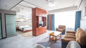 Una habitación de hotel moderna con una cama, un armario de madera, un sofá y un televisor.