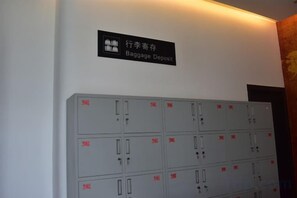 A wall-mounted sign indicating a baggage deposit area, with multiple grey lockers below. - Tianzihu Boutique Hotel (Anji)