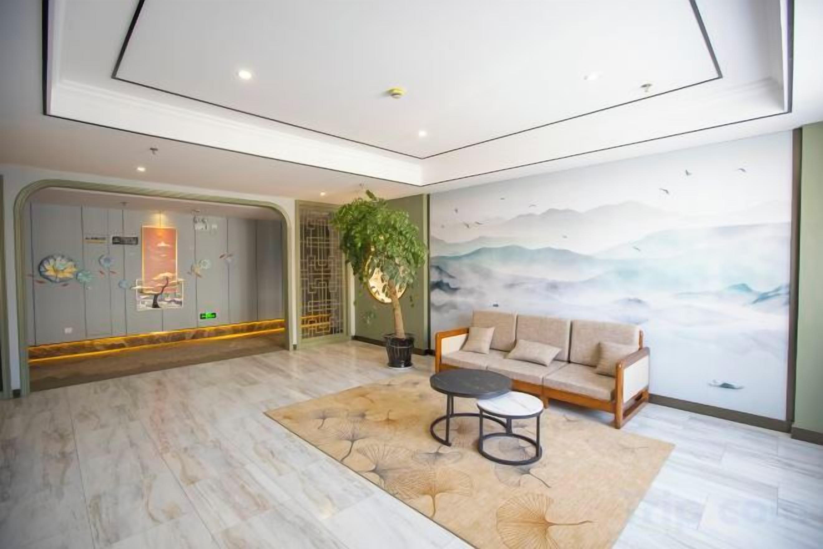 A hotel lobby with a marble floor, a sofa, a small table, and a mural on the wall.