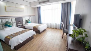 Habitación de hotel con dos camas, un escritorio, una silla y un televisor.