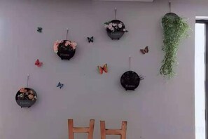 A wall with multiple hanging decorations including circular wall hangings with the word 'Home' and a hanging green plant. - Tianzihu Boutique Hotel (Anji)