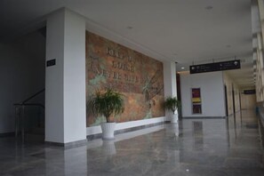 A hallway with a large wall mural, potted plants, and directional signs. - Tianzihu Boutique Hotel (Anji)
