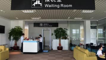Een wachtruimte met een receptiebalie, een beveiligingscontrolezone en zitplaatsen.