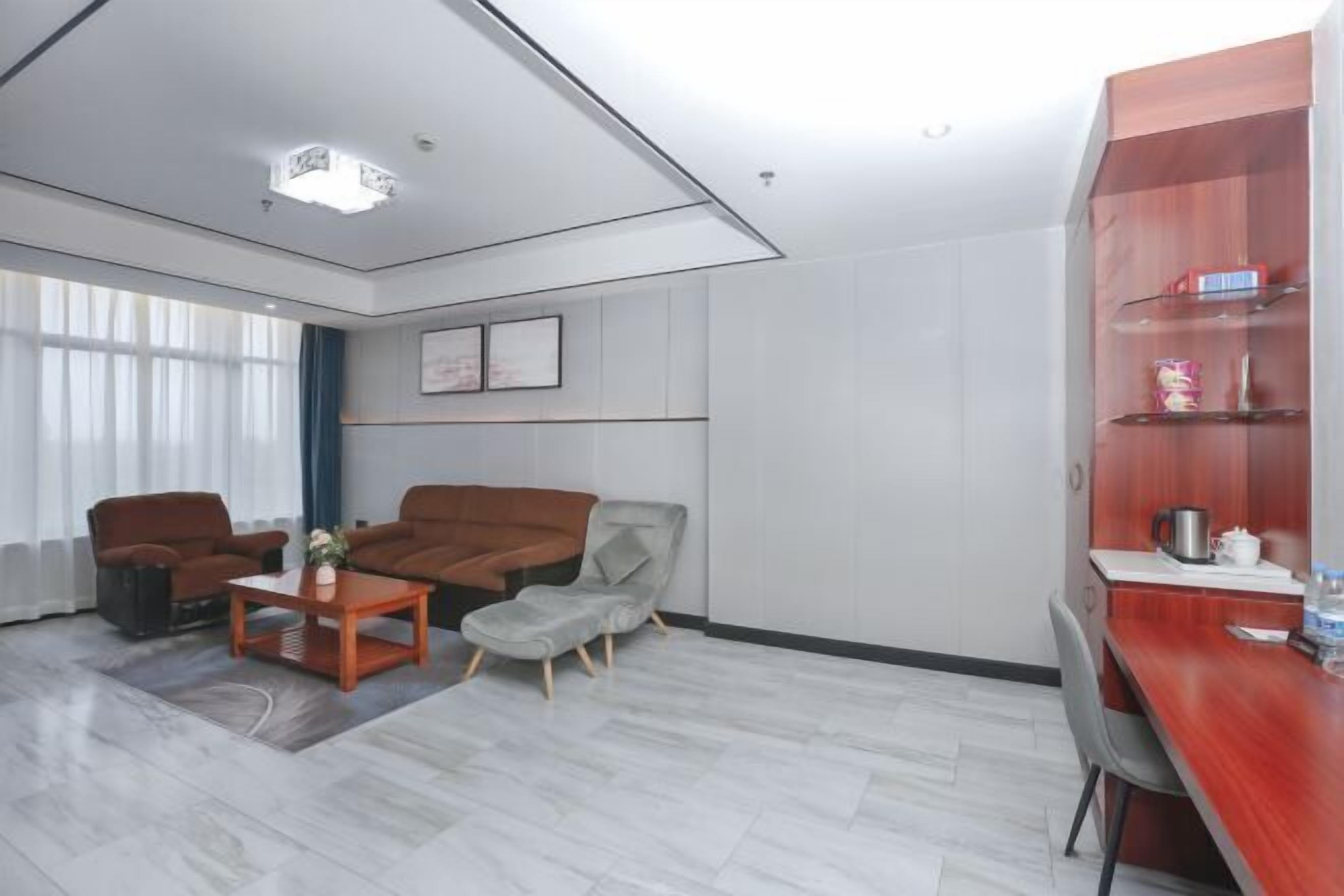 A modern living room with a sofa, armchairs, a coffee table, and a wooden desk.
