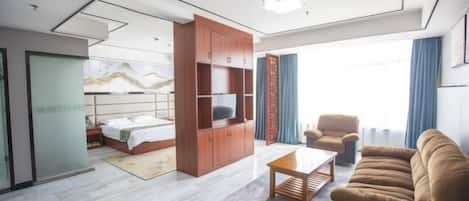 Une chambre d’hôtel moderne comprenant un lit, une armoire en bois avec un téléviseur, un canapé et une table basse.