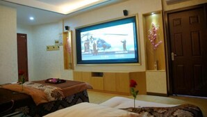 Una habitación con televisor montado en la pared, una camilla de masaje y una puerta.