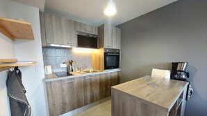 Una cocina moderna con armarios de madera, horno empotrado y cafetera.