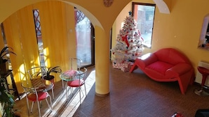 Un salón amplio con árbol de Navidad, sillas rojas y un ventanal grande.