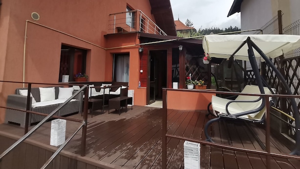 Una terraza de madera con mobiliario exterior y una zona cubierta.