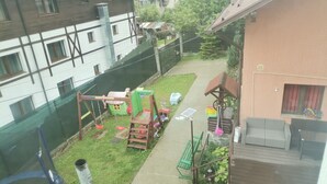 Un barrio residencial con un parque infantil, césped verde y una terraza de madera.