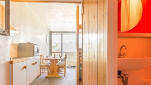 Un couloir étroit avec une table et des chaises en bois, une petite kitchenette et une vue par la fenêtre.